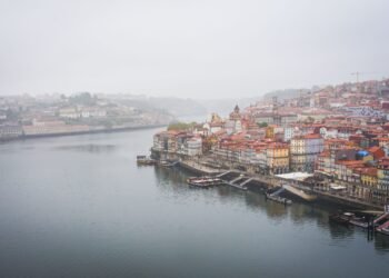 Aerial view of Porto's colorful riverside buildings along the Douro River under overcast skies.