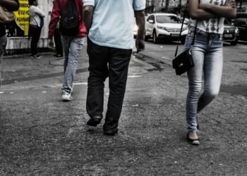Busy city street scene featuring pedestrians walking on asphalt in daylight.