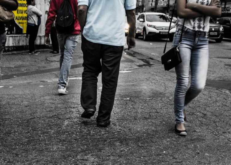 Busy city street scene featuring pedestrians walking on asphalt in daylight.