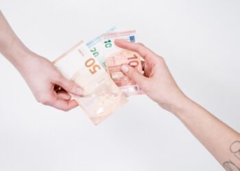 Close-up of hands exchanging euro banknotes, symbolizing financial transactions and currency exchange.