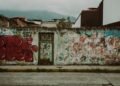 Colorful graffiti covers a street wall in Mérida, Venezuela, with urban decay and mountains in the background.