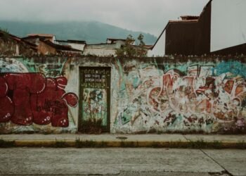 Colorful graffiti covers a street wall in Mérida, Venezuela, with urban decay and mountains in the background.