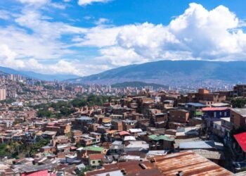 Scenic view of Medellín's diverse architecture and mountains under a bright blue sky.