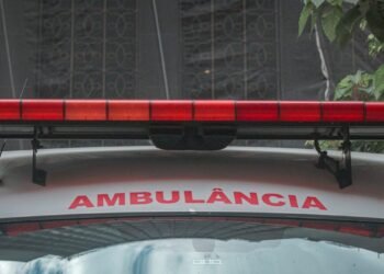 A close-up view of a city ambulance with a red siren light and Portuguese text 'AMBULÂNCIA'
