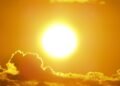 A stunning view of the golden sun shining through clouds at sunset, casting a warm glow.