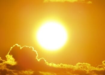 A stunning view of the golden sun shining through clouds at sunset, casting a warm glow.