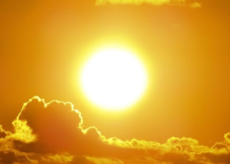 A stunning view of the golden sun shining through clouds at sunset, casting a warm glow.