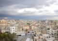 Aerial view of Qalqilya's urban cityscape under dramatic clouds, showcasing diverse architecture.