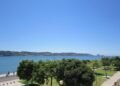 Explore Lisbon's beautiful waterfront with lush greenery and a clear blue sky, perfect for summer strolls.