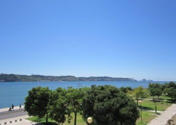Explore Lisbon's beautiful waterfront with lush greenery and a clear blue sky, perfect for summer strolls.