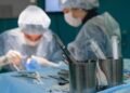 Focused surgeons in an operating room performing surgery with medical instruments.