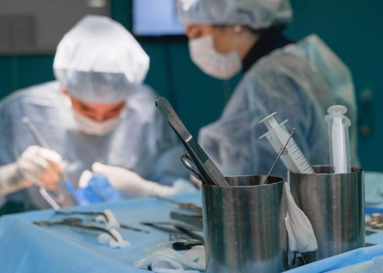 Focused surgeons in an operating room performing surgery with medical instruments.