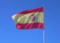 Spanish national flag waving against a clear blue sky in Cádiz, Andalucía.