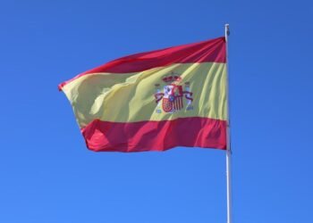 Spanish national flag waving against a clear blue sky in Cádiz, Andalucía.