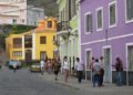 a group of people walking down a street next to colorful buildings