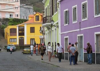 a group of people walking down a street next to colorful buildings