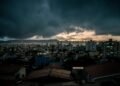 city with high rise buildings under gray clouds during night time