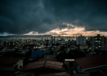 city with high rise buildings under gray clouds during night time