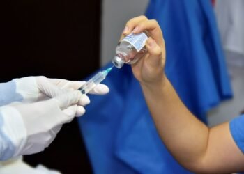close up of pouring liquid from bottle to syringe
