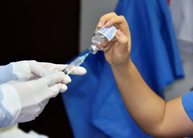 close up of pouring liquid from bottle to syringe