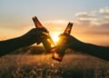 photography of person holding glass bottles during sunset