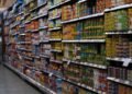 A supermarket aisle filled with various canned goods on shelves, showcasing retail diversity.