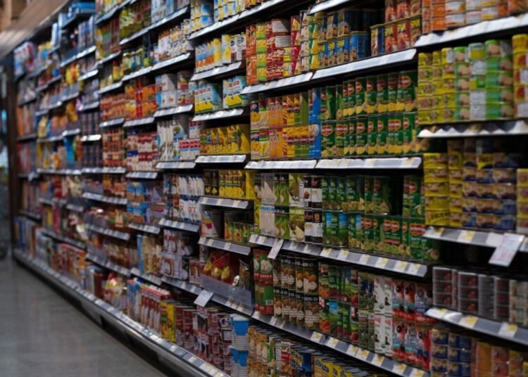 A supermarket aisle filled with various canned goods on shelves, showcasing retail diversity.