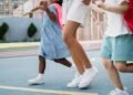 Kids holding hands and walking joyfully on a colorful outdoor playground.