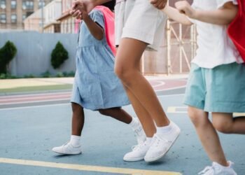 Kids holding hands and walking joyfully on a colorful outdoor playground.
