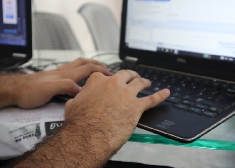 a man is typing on a laptop computer