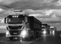Black and white photo of trucks driving on a highway in Buenos Aires, Argentina at dusk.